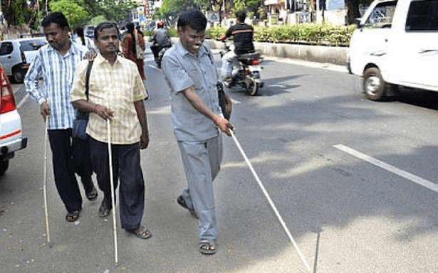 Blind men with white canes navigating traffic together
